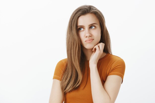 Jolie fille réfléchie et troublée pensant, regardant indécise, prenant une décision