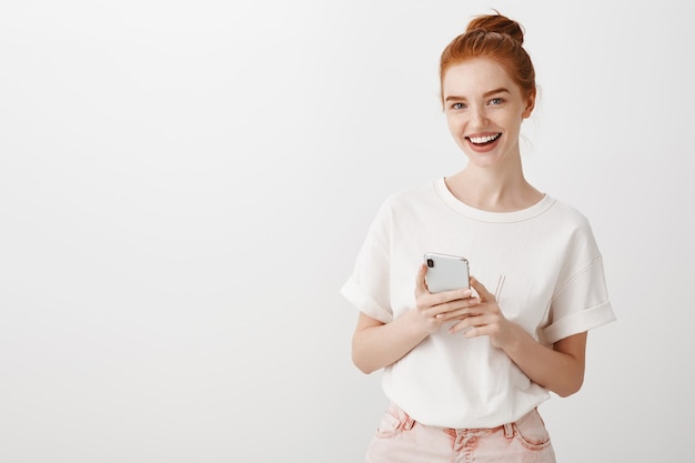 Jolie fille rousse avec smartphone souriant