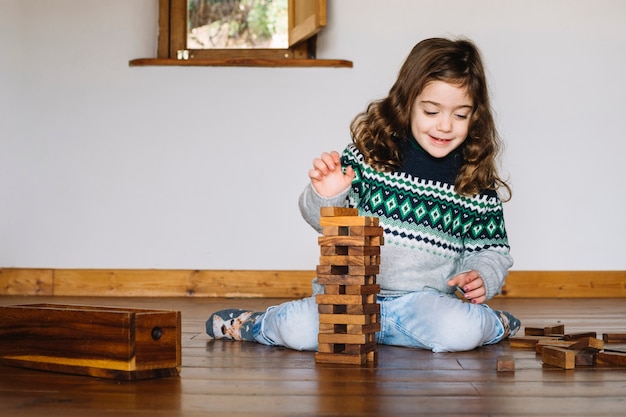 Jolie fille souriante empilant des blocs de bois