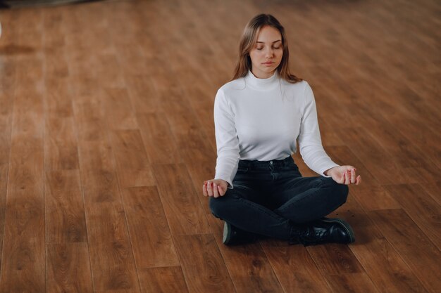 Jolie fille de style commercial est assise sur le sol en position de lotus. yoga au bureau, détente au travail. recherche de l'harmonie dans la vie des affaires. le yoga et un état d'esprit positif harmonieux.