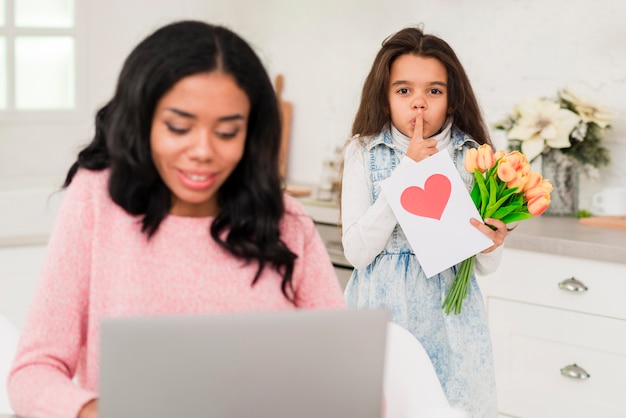 Jolie fille surprenant sa maman tout en travaillant