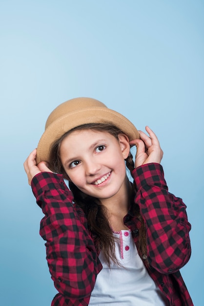 Jolie fille tenant un chapeau sur la tête