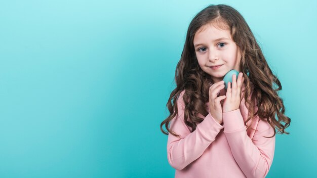 Jolie fille tenant un oeuf de Pâques bleu