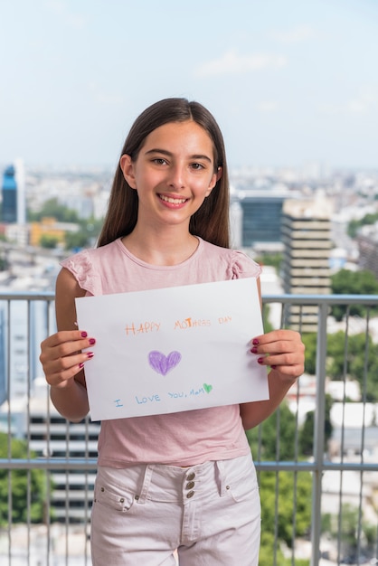 Jolie fille tenant papier avec inscription heureuse fête des mères