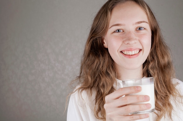 Jolie fille tenant un verre de lait à l'intérieur