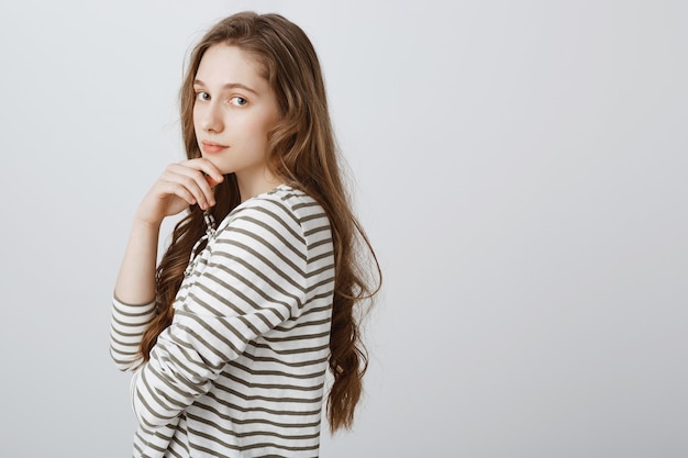 Jolie fille tendre et romantique posant sur un mur blanc