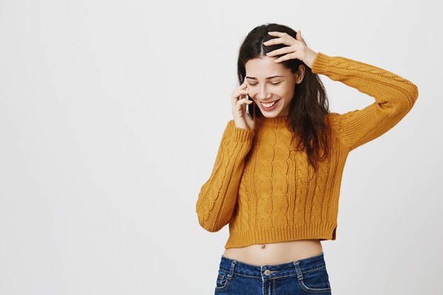 Jolie fille à la timide tout en parlant au téléphone, souriant heureux