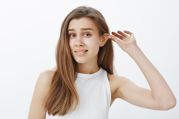 jolie fille tirant son oreille, fatiguée d'écouter des mensonges et des excuses