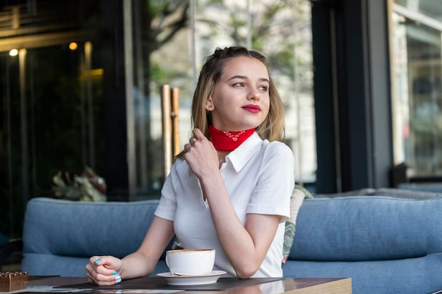 Photo gratuite jolie jeune blonde assise au restaurant et regardant au loin