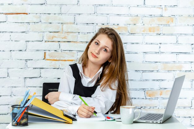 Jolie jeune étudiante assise sur fond blanc et regardant l'objectif Photo de haute qualité