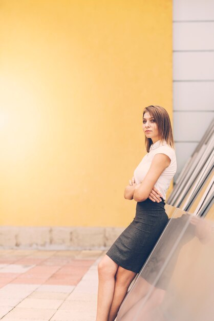 Jolie jeune femme d&#39;affaires s&#39;appuyant sur le mur