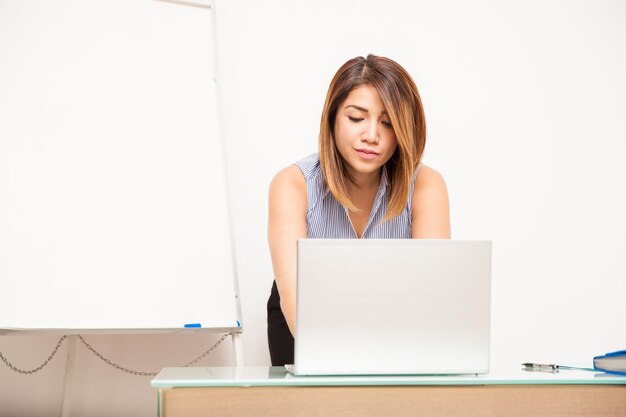 Jolie jeune femme d'affaires utilisant un ordinateur portable et organisant une présentation dans un bureau