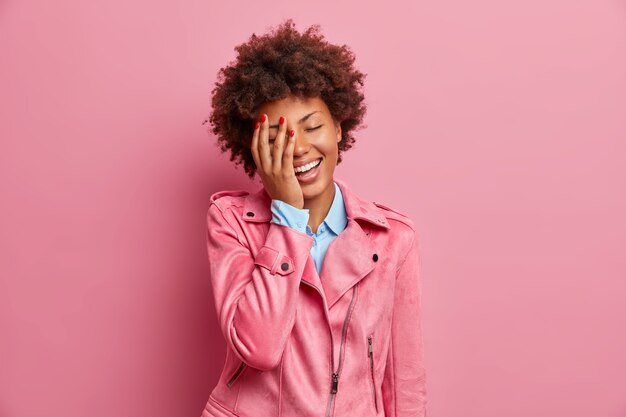 Jolie jeune femme afro-américaine ravie fait face à la paume et rit exprime joyeusement des émotions positives