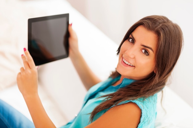 Jolie jeune femme à l'aide de tablette numérique à la maison