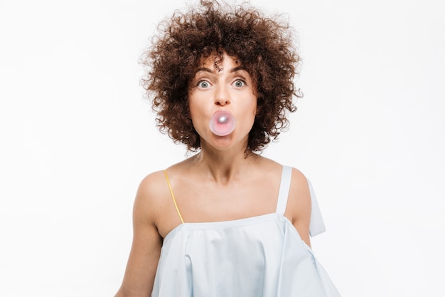 Jolie jeune femme aux cheveux bouclés, soufflant des bulles