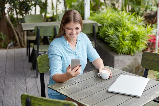 Jolie jeune femme aux cheveux longs assis dans un café avec téléphone