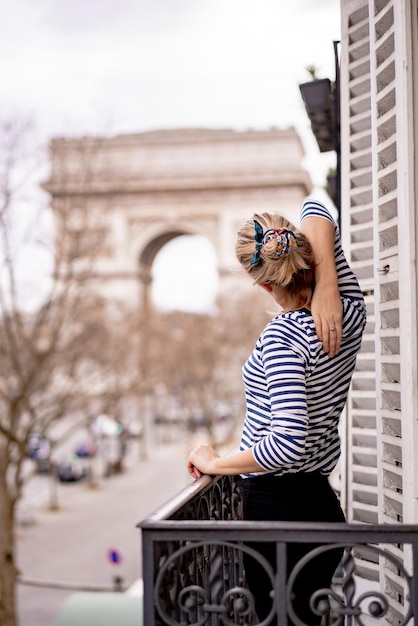 Jolie jeune femme sur balcon le matin dans la ville de Paris. vue sur l'arc de triomphe.