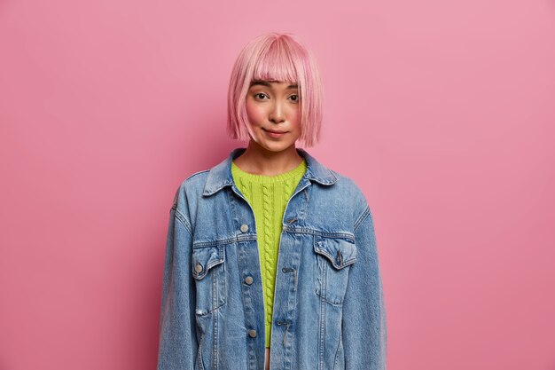 Jolie jeune femme belle a une conversation privée, a une coiffure bob, une perruque de cheveux roses, vêtue d'une veste en jean à la mode