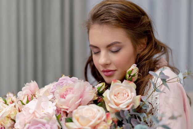 Jolie jeune femme avec bouquet de centaines de fleurs passe du temps à la maison.