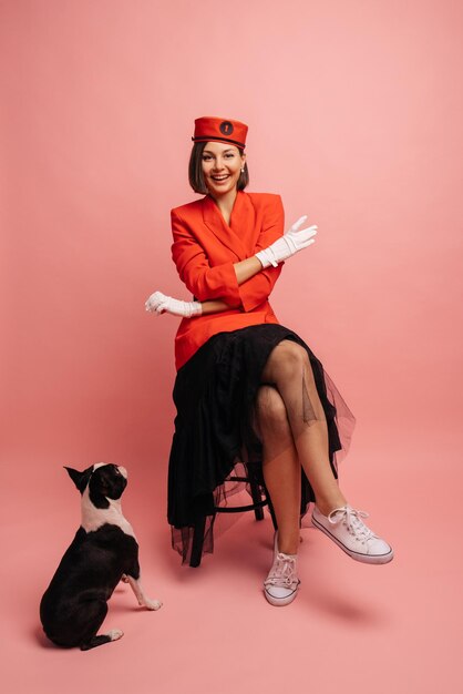 Jolie jeune femme caucasienne aux cheveux courts foncés est assise avec son bouledogue sur fond rose Véritable amitié merveilleux moments heureux