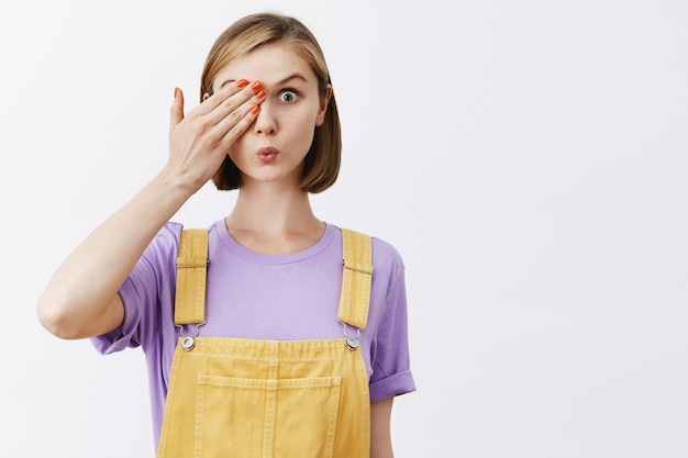 jolie jeune femme couvrir un œil et à la surprise