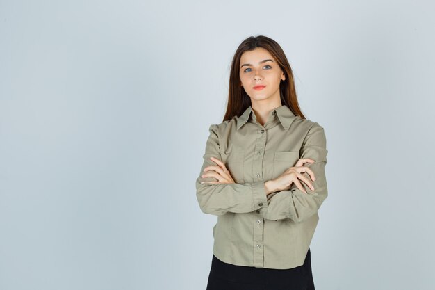 Jolie jeune femme debout avec les bras croisés en chemise, jupe et fière allure. vue de face.