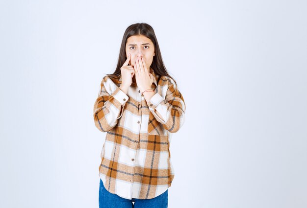 Jolie jeune femme debout sur un mur blanc.