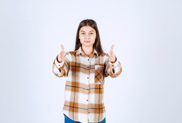 Jolie jeune femme debout sur un mur blanc.