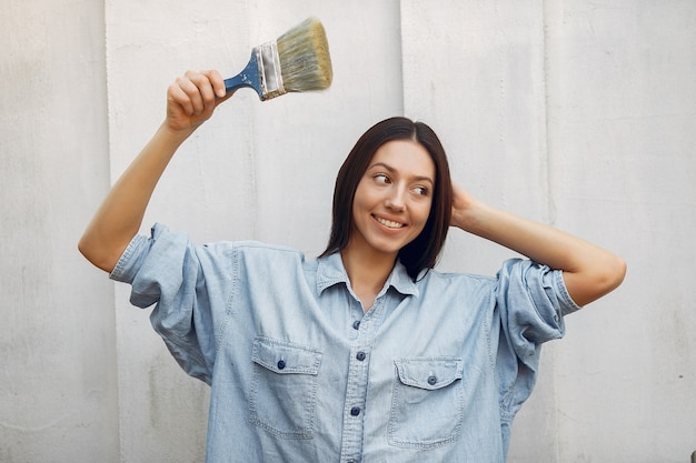 Jolie jeune femme debout près du mur avec une brosse