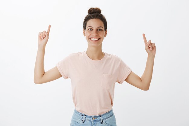 Jolie jeune femme élégante posant contre le mur blanc