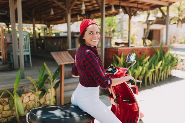 Jolie jeune femme élégante se retourne et souriant tout en conduisant sa moto dans le parc au soleil