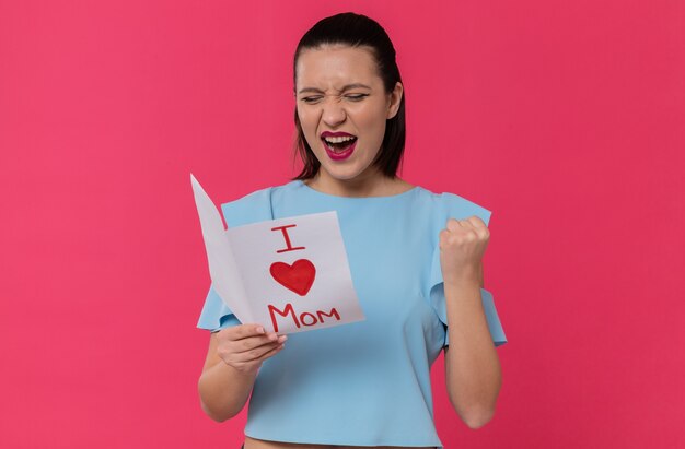 Jolie jeune femme joyeuse lisant la lettre de son enfant et gardant le poing