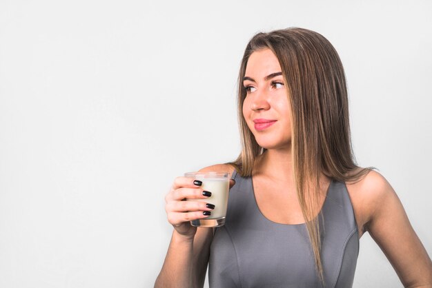 Jolie jeune femme joyeuse en vêtements de sport avec verre de lait