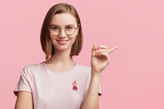 Jolie jeune femme avec des lunettes rondes et un ruban pour la sensibilisation au cancer du sein