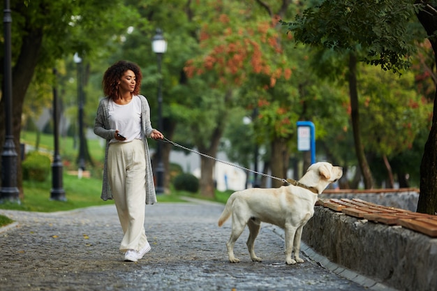 Jolie jeune femme marchant avec un chien dans le parc le matin