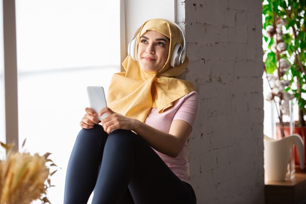 jolie jeune femme musulmane à la maison pendant la quarantaine et l'auto-isolation, à l'aide de tablette pour selfie ou vidéocall, leçons en ligne