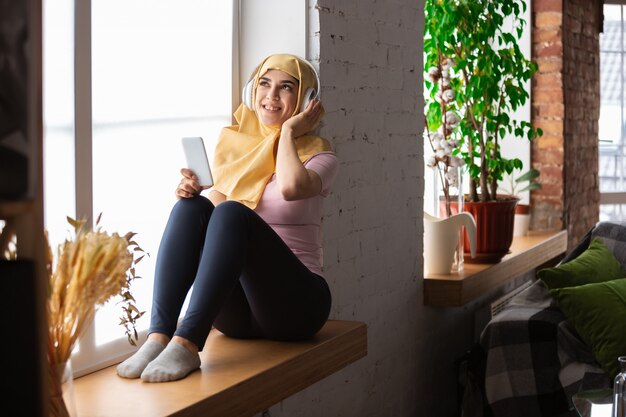 jolie jeune femme musulmane à la maison pendant la quarantaine et l'auto-isolation, à l'aide de tablette pour selfie ou vidéocall, leçons en ligne