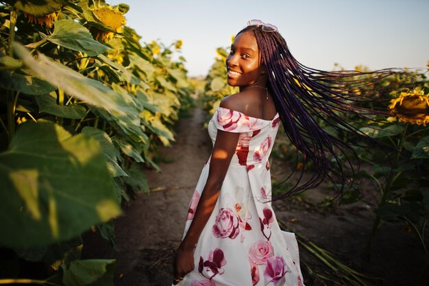 Jolie jeune femme noire portant une robe d'été pose dans un champ de tournesols