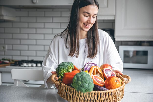 Jolie jeune femme et un panier de fruits et légumes dans la cuisine