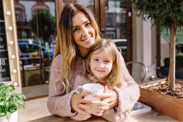 Jolie jeune femme avec petite belle fille vêtue de chandails chauds dans la rue