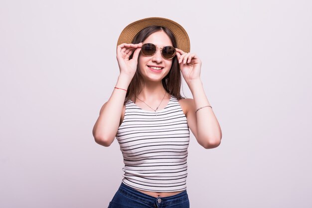 Jolie jeune femme portant un chapeau, lunettes de soleil isolé sur fond blanc