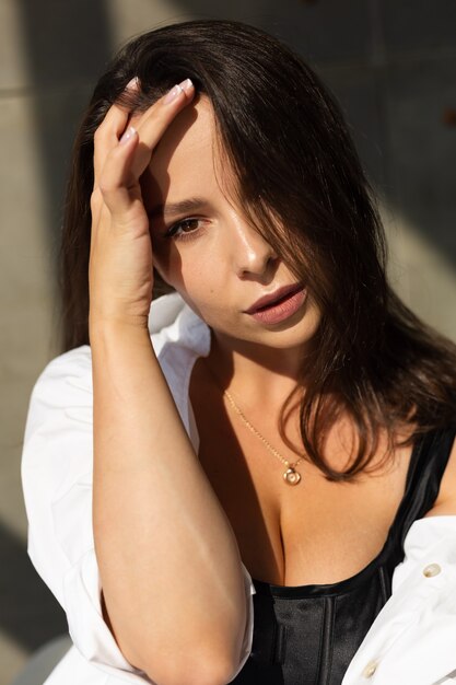 Jolie jeune femme posant sur une chaise blanche en studio