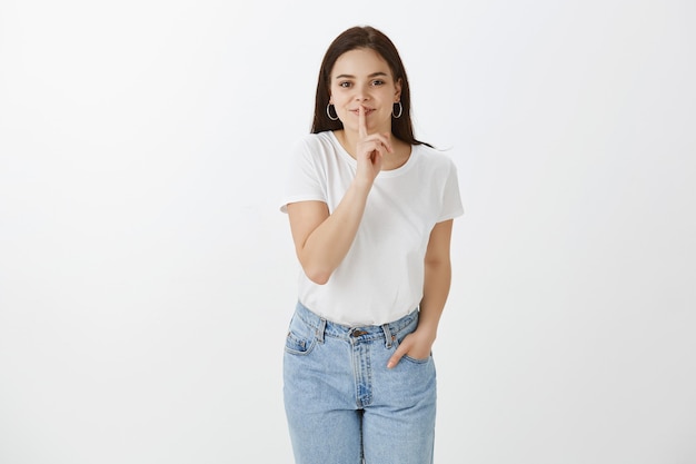 Jolie jeune femme posant contre le mur blanc