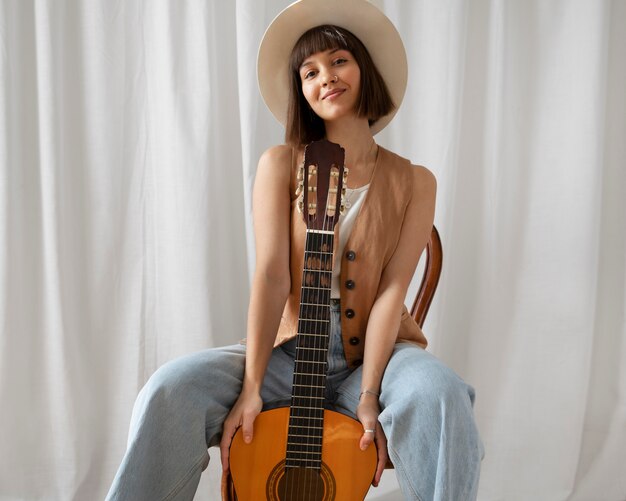 Jolie jeune femme posant avec une guitare à l'intérieur
