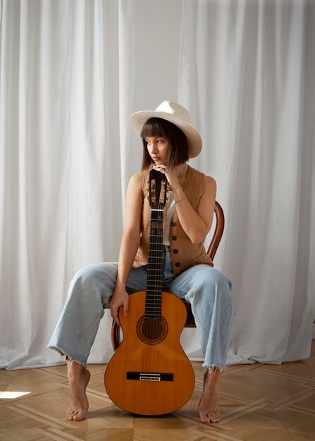 Jolie jeune femme posant avec une guitare à l'intérieur