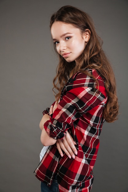 Jolie jeune femme posant isolé sur mur gris