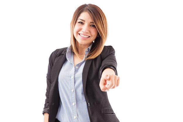 Jolie jeune femme recruteur pointant vers la caméra et souriant sur un fond blanc