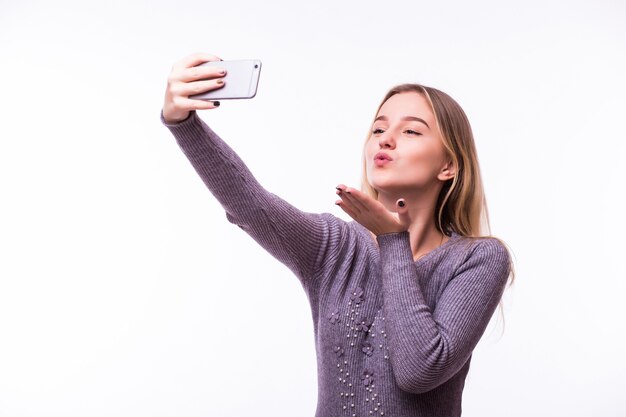 Jolie jeune femme de rêve heureux en t-shirt rayé isolé sur un mur blanc prenant un selfie et donnant l'air-baiser