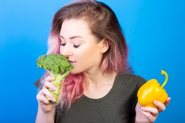 Jolie jeune femme sentant le brocoli frais dans sa main droite