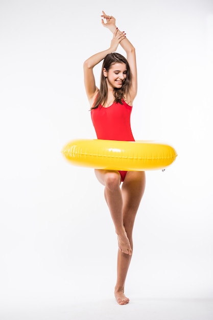 Jolie jeune femme sexy en maillot de bain rouge tient un matelas pneumatique rond jaune isolé sur fond blanc